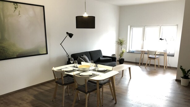Ein modernes Wohnzimmer mit Essbereich, einer Couch und einem großen Fenster.