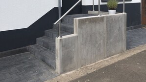 Ein modernes Gebäude mit weißer Fassade, einer schwarzen Tür und einem kleinen Fenster.