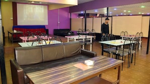 A conference room with a large screen, tables, chairs, and a sofa. - Kathmadu Fawlty Home (Kathmandu)