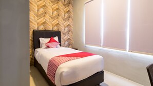 Une chambre d’hôtel avec un lit, un mur orné d’un motif en chevrons, une grande fenêtre et un plafond blanc.