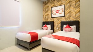 Une chambre d’hôtel avec deux lits, chacun agrémenté de draps rouges et blancs, un mur en bois avec un motif en chevrons et un tableau encadré avec le mot « ovo » et un motif floral.