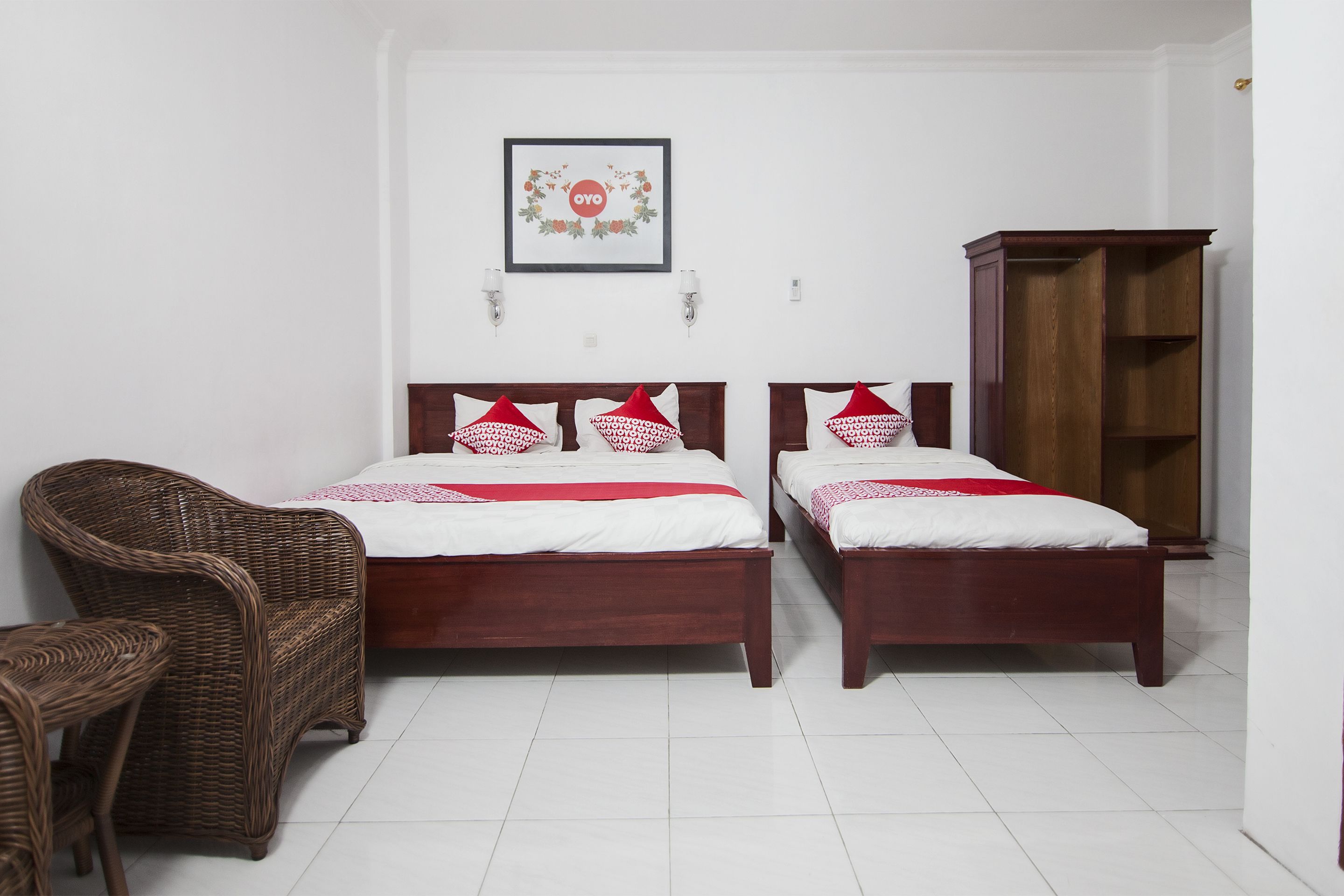Quarto com duas camas de madeira, uma cadeira de vime e um guarda-roupa.