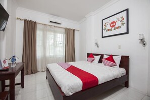 Une chambre d’hôtel avec un lit, un bureau, une télévision et un tableau encadré au mur.