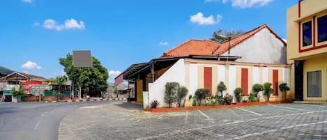 A paved street with a building featuring a red-tiled roof and a white facade with vertical red and beige stripes.