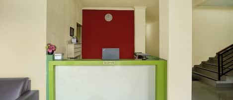 A reception desk with a clock, a reception area, and a staircase.