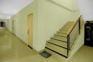 Eine Treppe mit hölzernem Geländer und schwarzen Metallspindeln, die zu einer Zwischenebene mit einer Tür führt.
