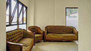 Ein Zimmer mit zwei braunen Polster-Sofas mit Holzarmlehnen und -beinen, vor einer Wand mit großen Fenstern platziert.