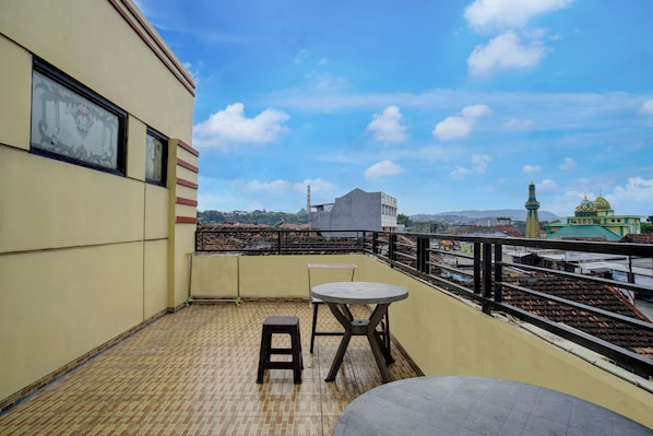 A balcony with a tiled floor, a small table, and a stool.