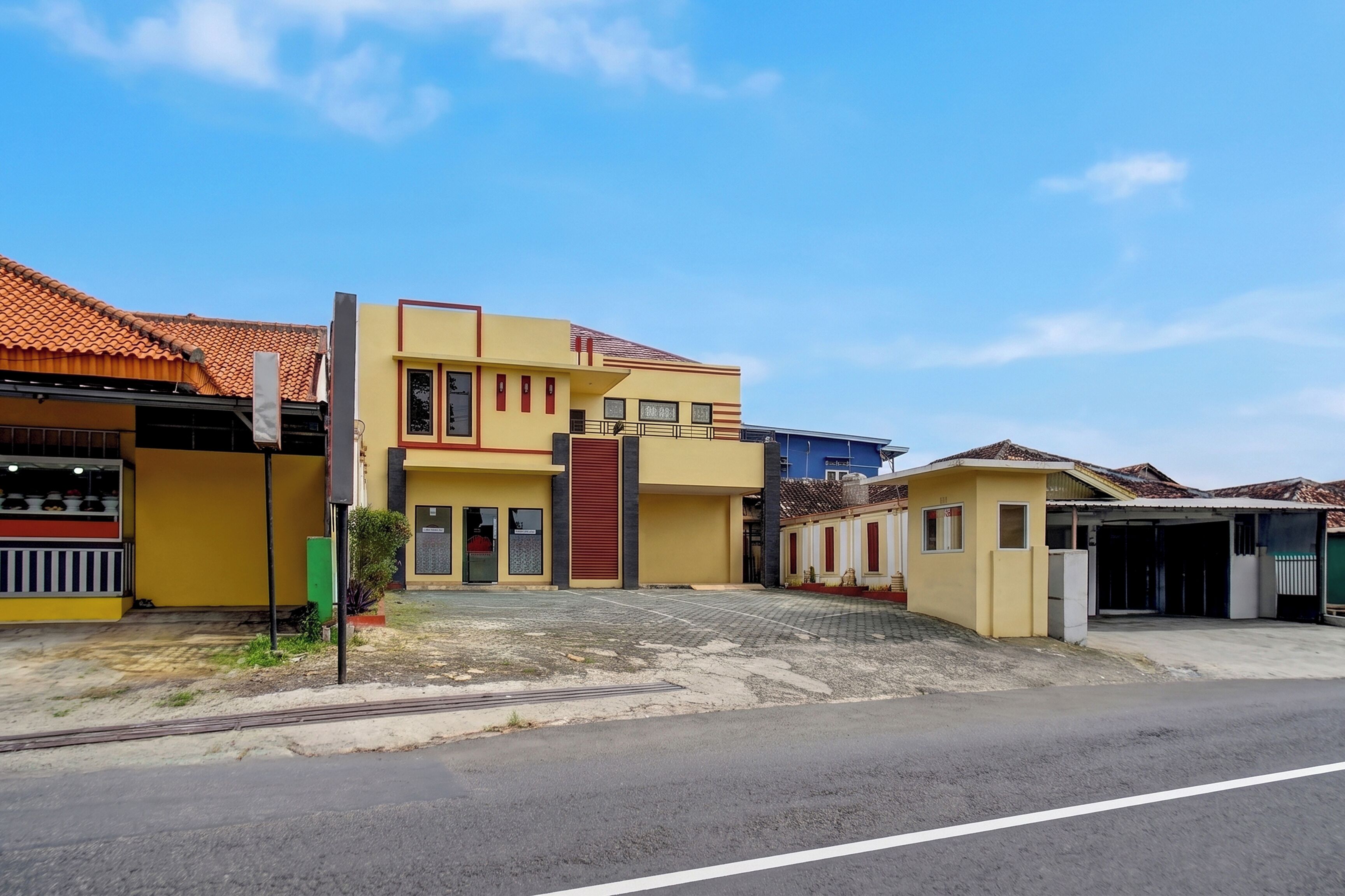A two-story building with a tiled roof, a flat entrance, and a paved driveway.