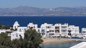 Une ville côtière aux bâtiments blancs, avec une plage et des montagnes en arrière-plan.