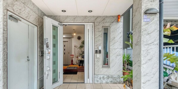 A hotel entrance with marble walls, a glass door, and a view into the interior.
