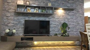 Una sala de estar moderna con pared de piedra, televisor de pantalla plana, estanterías empotradas y una mesa de centro de madera.