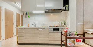 Une cuisine moderne dotée d’un îlot central, d’appareils électroménagers intégrés et d’un coin repas avec une table en bois.