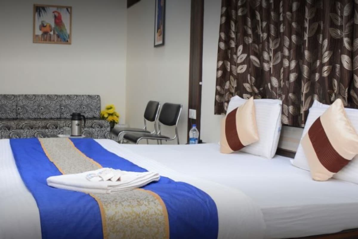 A hotel room with a large bed, a sofa, a coffee table, and a painting on the wall.