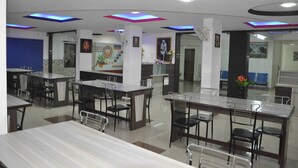 A modern restaurant with multiple dining areas, including a bar and a counter with chairs. - Hotel Sai Palace (Bhinmal)