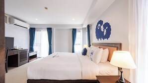 Quarto de hotel com cama, mesa de cabeceira, luminária e ar condicionado fixado na parede.