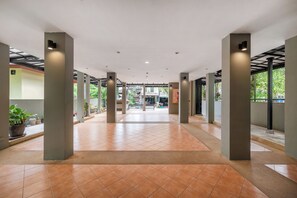 Un hall d’entrée spacieux, doté d’un sol carrelé, de grandes colonnes et offrant une vue sur l’extérieur.