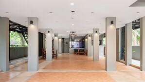 Um hall amplo com piso de azulejos, mobiliário de madeira e grandes pilares.