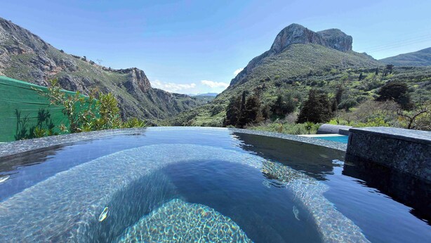 Una piscina cristalina con montañas al fondo.