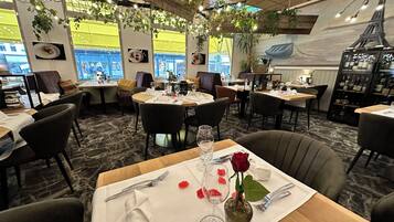 Un restaurante con mesas redondas, sillas y vistas a la Torre Eiffel a través de amplios ventanales.