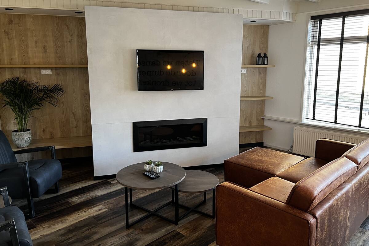 A modern living room with a fireplace, a mounted TV, and a seating area with a sofa and chairs.
