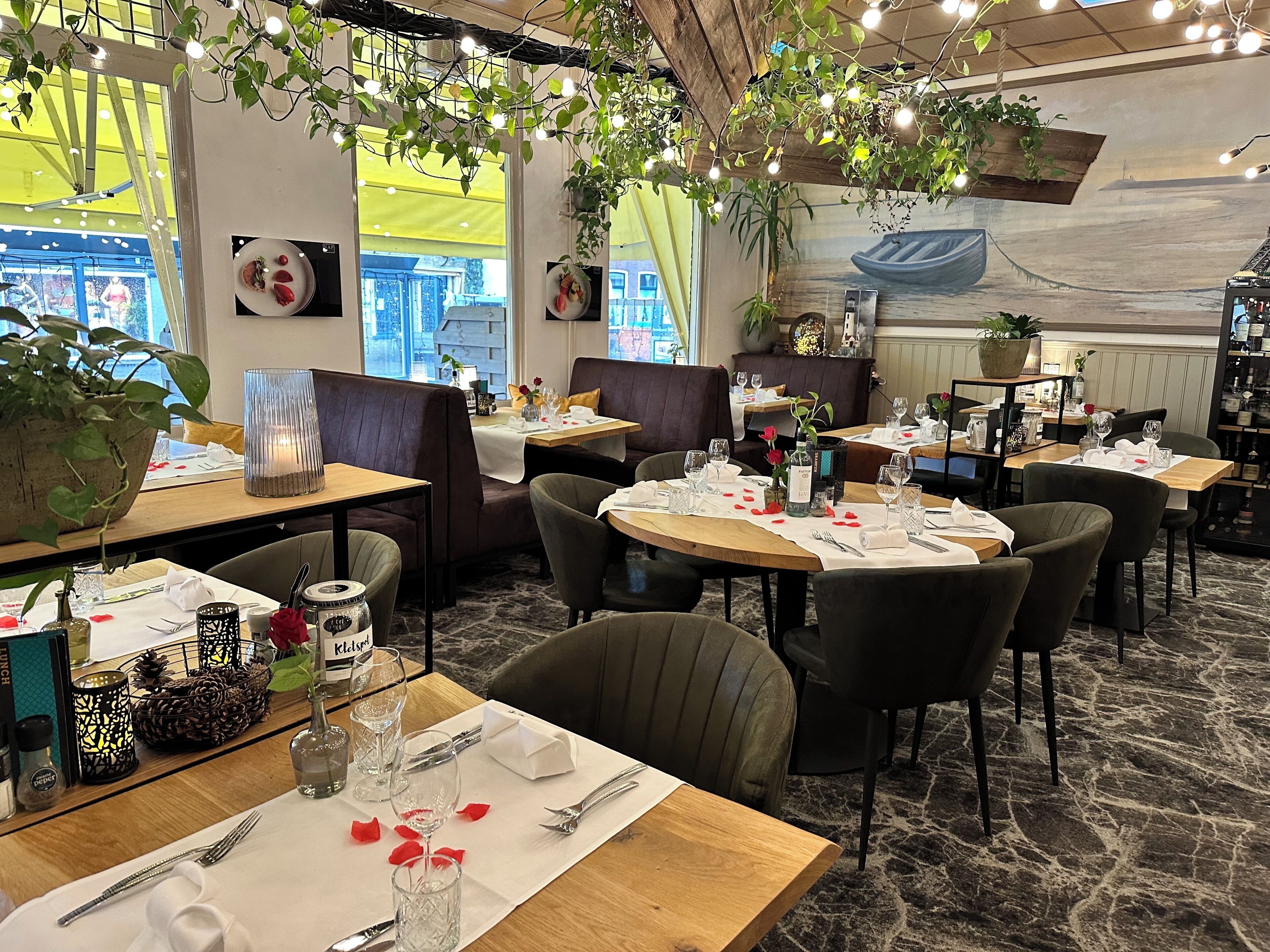 A restaurant with wooden tables, comfortable seating, and decorative plants.