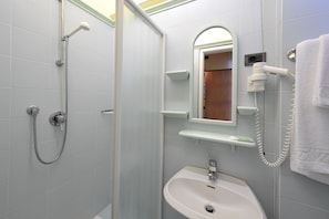 Un baño con ducha, lavabo y perchero para toallas.