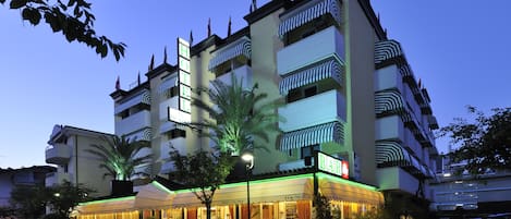 Un hotel de varios pisos con bar y restaurante en la planta baja, con balcones y un diseño arquitectónico moderno.