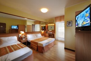 Habitación de hotel con dos camas, un escritorio, un televisor y un espejo.