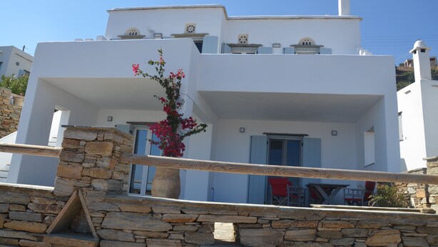 Un bâtiment blanc aux murs de pierre, doté d’un balcon et agrémenté d’une composition florale.