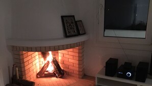 Un salon avec une cheminée, un canapé et un meuble pour la télévision, équipé d’enceintes.
