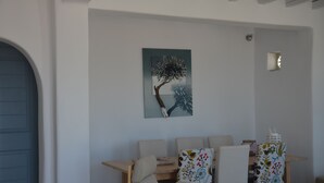 Un coin repas avec une table et des chaises, une œuvre d’art représentant un arbre accrochée au mur, et une porte.