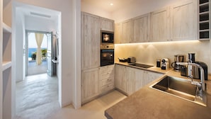 A modern kitchen with wooden cabinets, stainless steel appliances, and a view to the outside. - Villa Adrali, 4 bedrooms, private pool (ΘΗΡΑ)