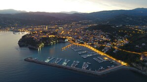 A coastal cityscape with a marina filled with boats, surrounded by hills and illuminated buildings. - La Via Del Porto (Agropoli)