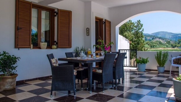 A terrace with a checkered floor, a table with chairs, and potted plants. - Welcome To Our Traditional Experience House (Ρέθυμνο)