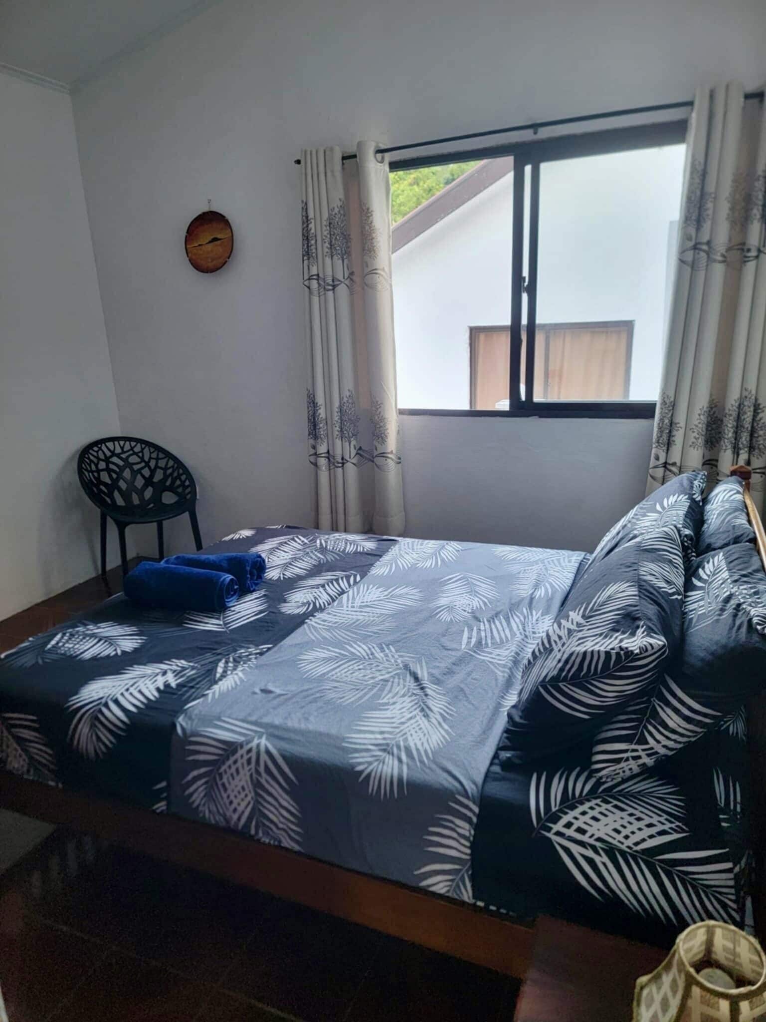 A room with a bed, a chair, and a window with curtains.