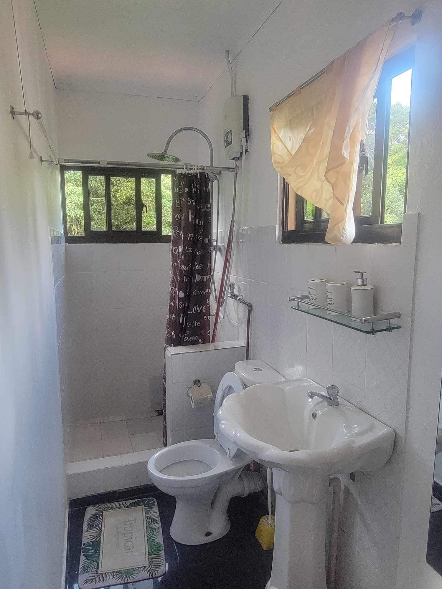 Une petite salle de bain simple, équipée de toilettes, d’un lavabo et d’une douche.