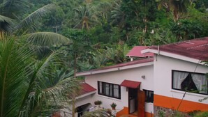 Un bâtiment à deux étages, doté d’un toit rouge et entouré d’une végétation tropicale luxuriante.