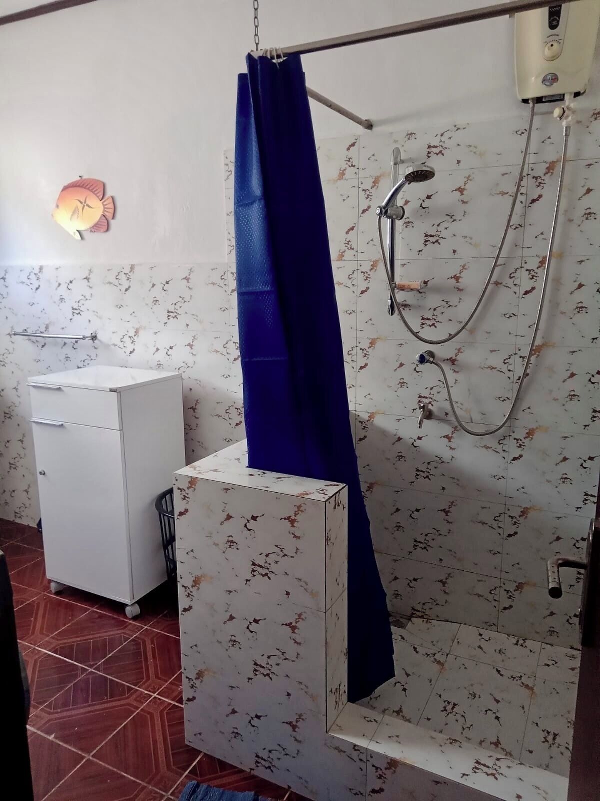 Une salle de bain avec une douche, un meuble blanc et un porte-serviettes.