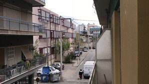 Una strada residenziale con edifici a più piani, un attraversamento pedonale, auto parcheggiate e un furgone in vista.