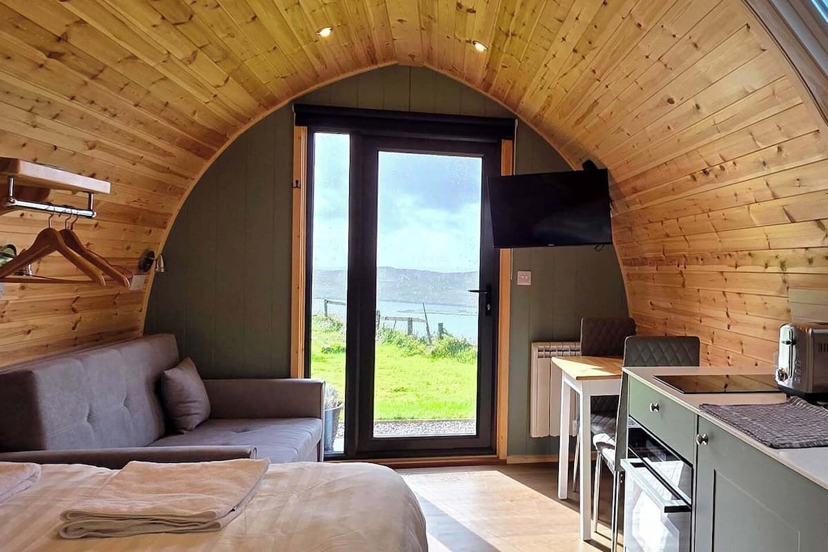 A cozy cabin with a loft bedroom, a dining area, and a kitchenette.
