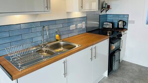 A modern kitchen with a wooden countertop, stainless steel sink, and a built-in oven. - The Westings (Whiteness)