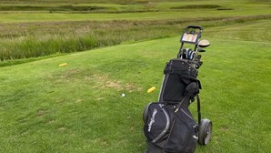 A golf bag on a grassy field with a backdrop of rolling hills. - The Westings (Whiteness)