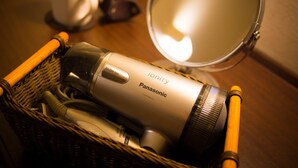 A basket containing a Panasonic hair dryer, a cup, and a mirror on a wooden surface. - Super Hotel Hachinohe Nagayokocho (Hachinohe)