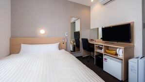 A hotel room with a bed, a desk, a chair, a television, a mirror, a small refrigerator, and an air conditioning unit. - Super Hotel Hachinohe Nagayokocho (Hachinohe)