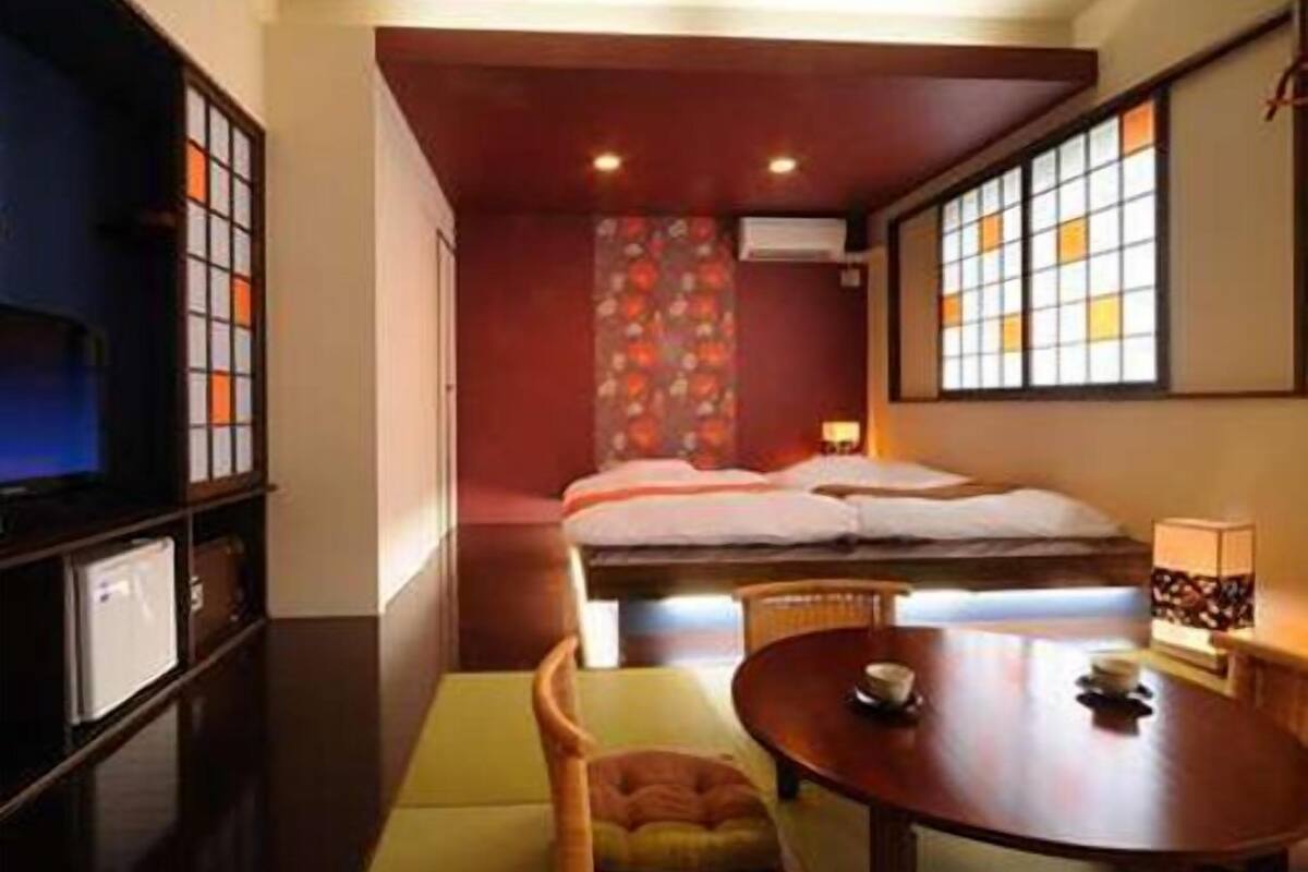 A compact hotel room with a bed, a small table, a chair, and a television.