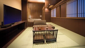 A traditional Japanese room with tatami flooring, a low table with cushions, a television on a stand, and sliding doors. - Aone Onsen Sankei no Yado Ryusen (Kawasaki)