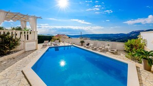 A swimming pool with a pergola, lounge chairs, and a view of the landscape. - Villa Lucia (dubrovnik)
