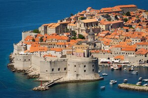 A coastal town with historic buildings, a prominent fortification, and a marina with boats.