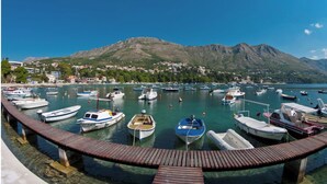 A marina with boats docked, a wooden pier, and a mountainous backdrop. - Villa Lucia (dubrovnik)